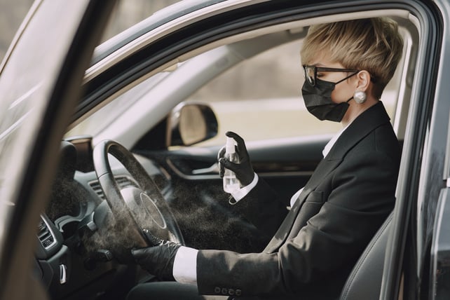 woman-in-formal-clothes-disinfecting-steering-wheel-of-car-4127517