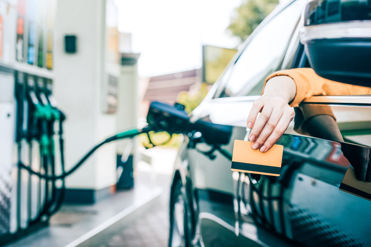 Driver holding a fleet card at a fuel pump while refuelling a commercial vehicle — illustrating how fleet card programs control fuel spend
