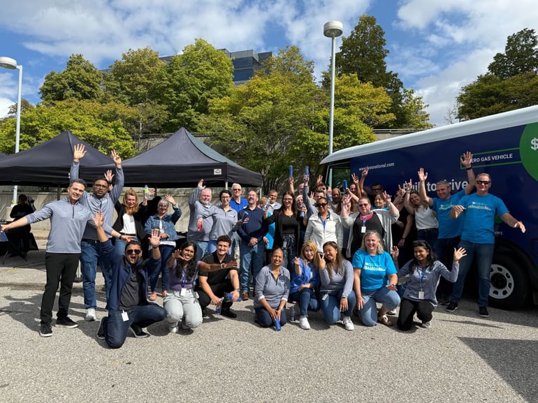 Foss National Leasing team gathered outdoors next to a zero-emission vehicle at a company event in Canada